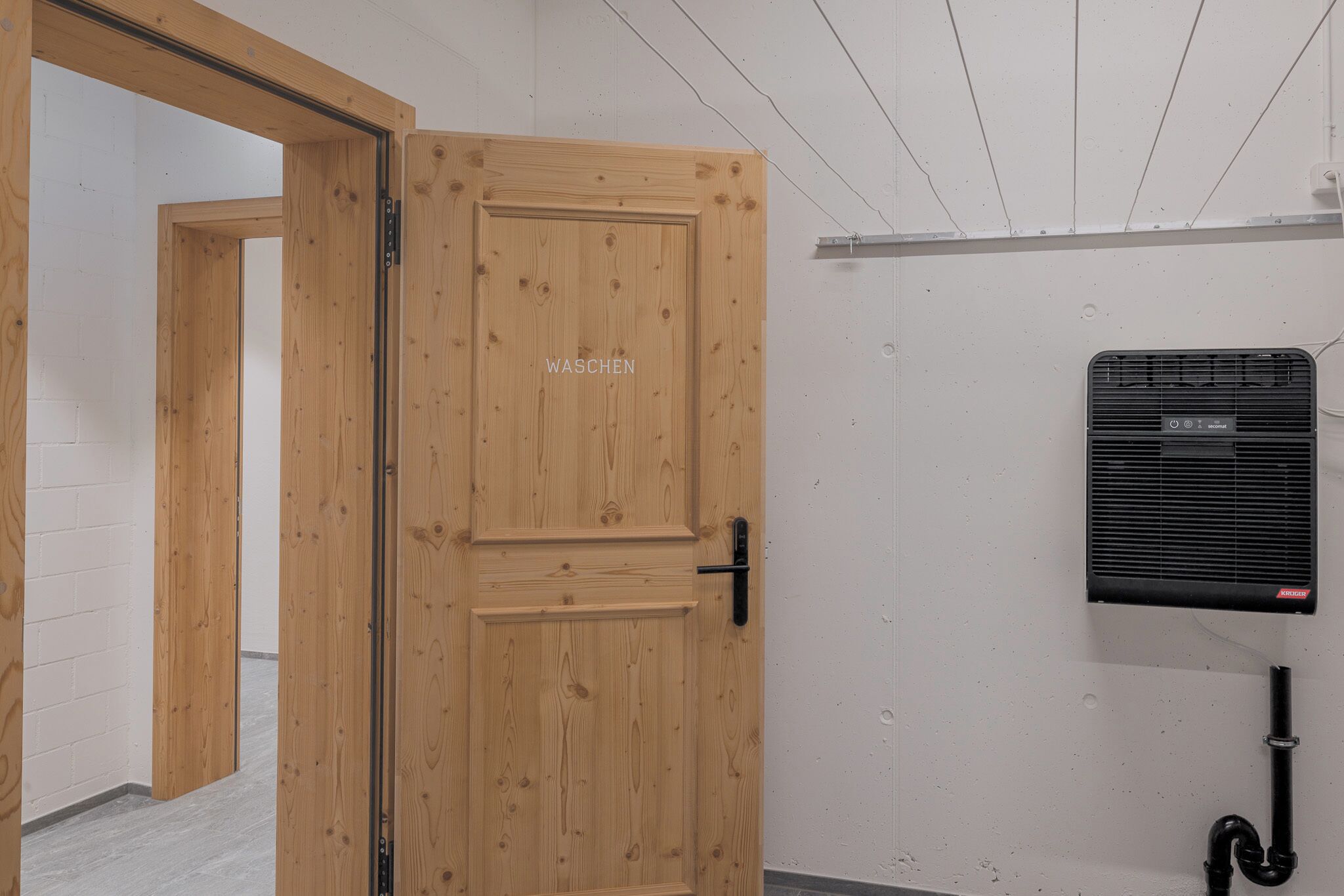 A wooden door with a handle and a label that reads "WASCHEN".
