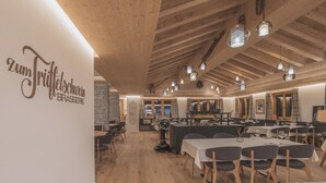 A restaurant interior with wooden beams, hanging pendant lights, and tables set for dining. - Val Saraina Resort Apartments Lenzerheide (Lantsch-Lenz)