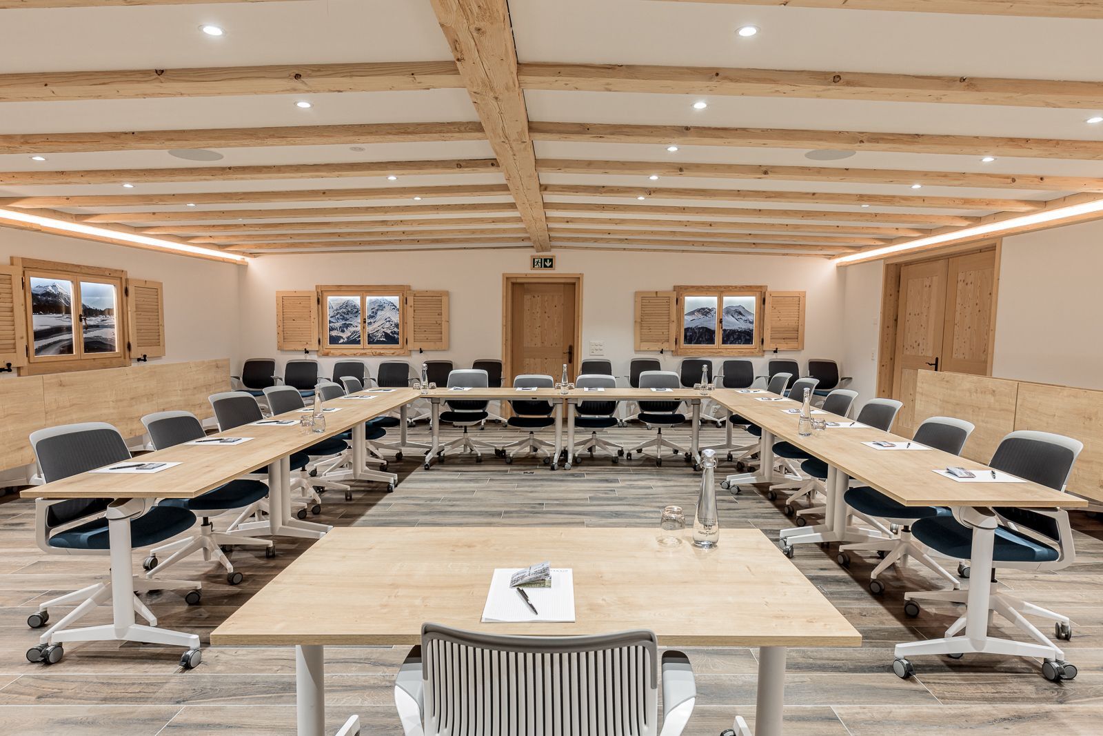 A conference room with a long table, multiple chairs, and wooden paneling on the walls.