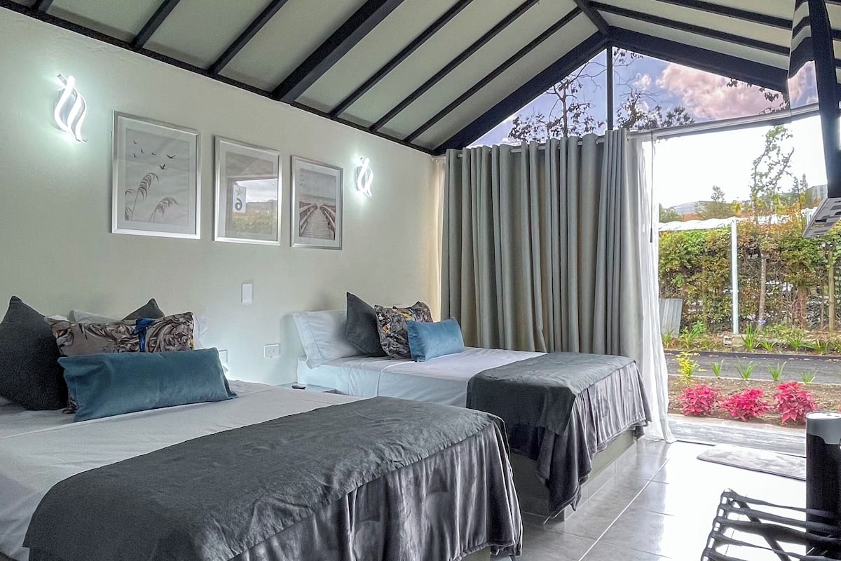 Una habitación moderna con dos camas, un ventanal grande y vistas al jardín.
