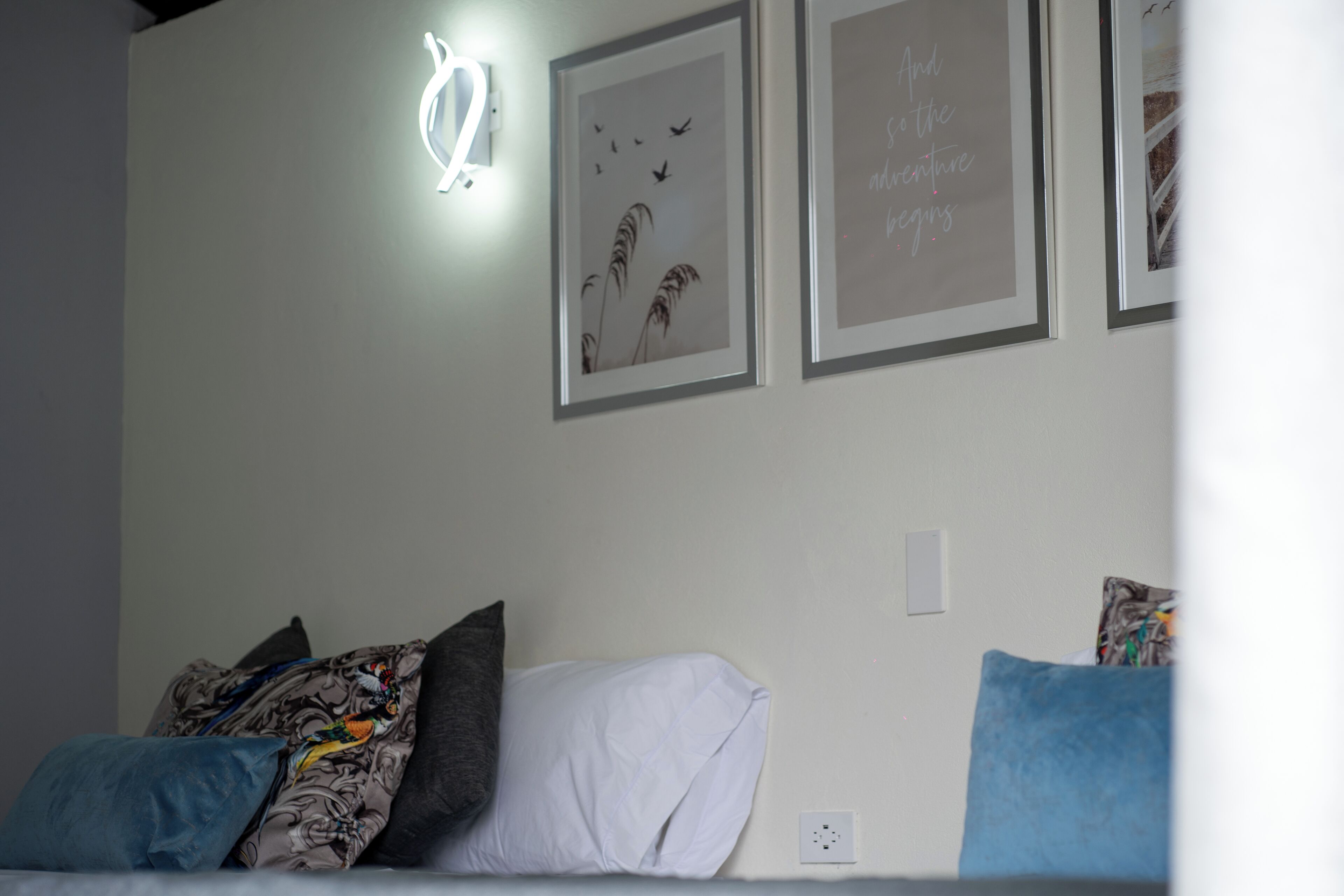 A bedroom with a bed, pillows, and framed pictures on the wall.