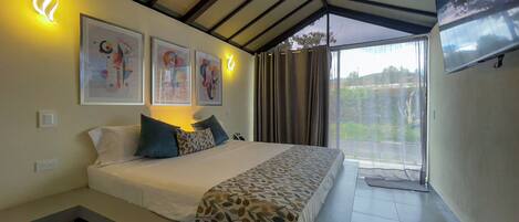 Una habitación de hotel con cama, televisión y obras de arte en la pared.