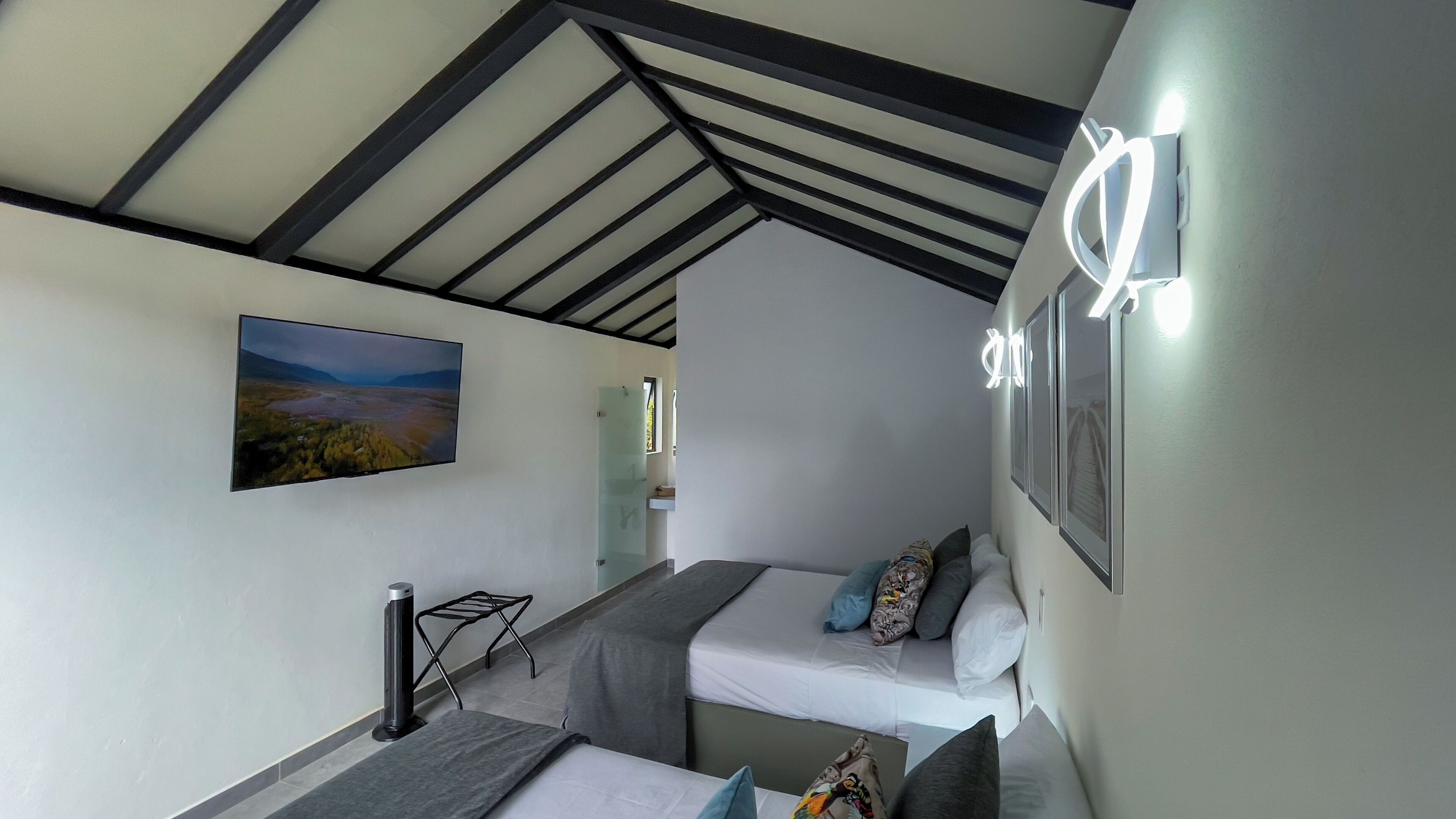 Een slaapkamer met twee bedden, een loopband, een schilderij en een plafond met zichtbare balken.