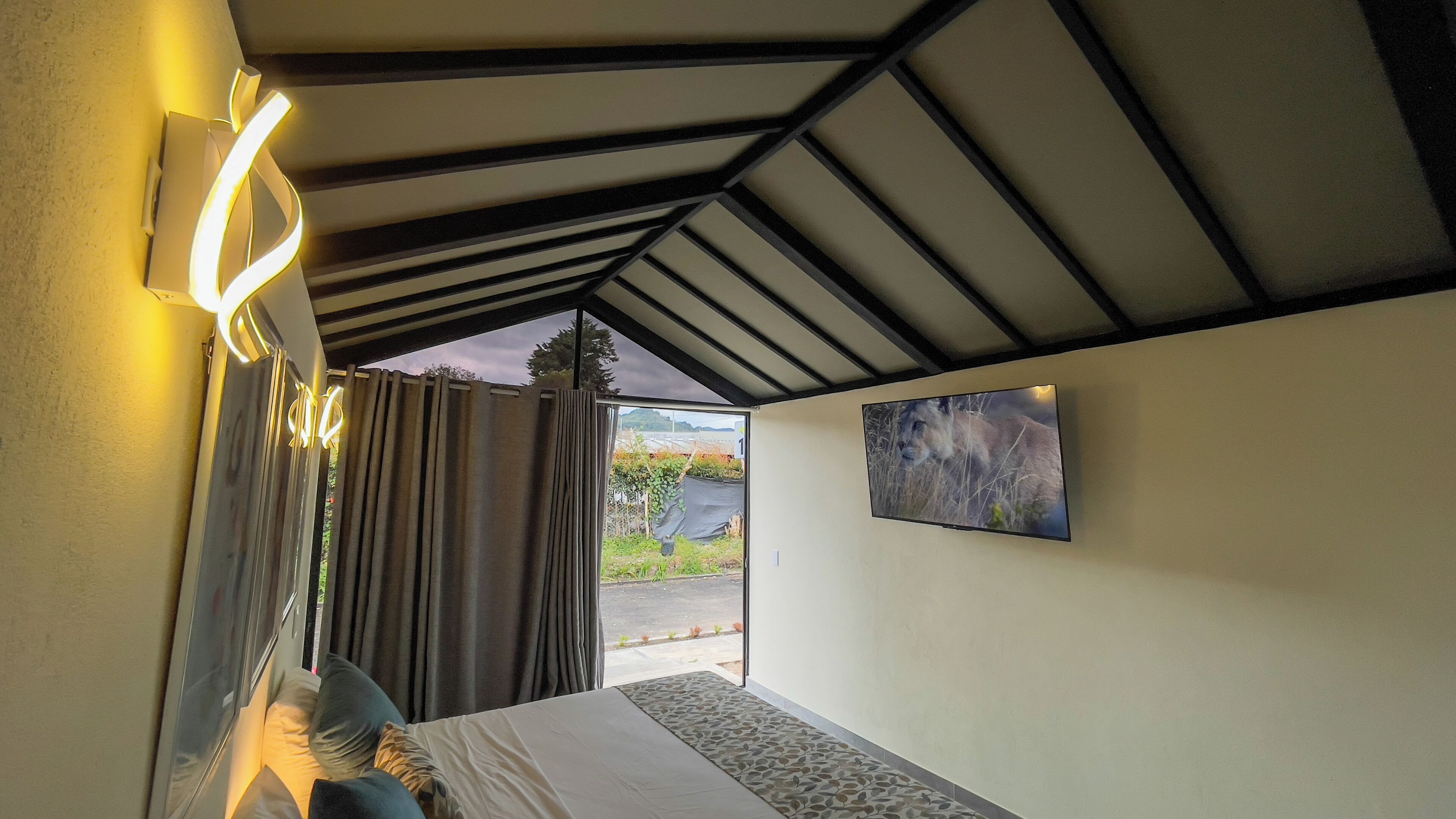 Una camera da letto con un letto, tende, una lampada a parete e un quadro.