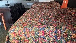 A hotel room with a large bed, a desk with a computer, a TV, and a bathroom visible in the background. - BUDEGT MOTOR LODGE (New Castle)