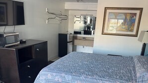 A hotel room with a bed, a desk with a computer, a microwave, and a refrigerator. - BUDEGT MOTOR LODGE (New Castle)