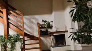 A staircase with wooden railings, a fireplace with a brick surround, and various potted plants. - CASA "INCANTO" Charming house with breathtaking views of Lake Como. (Comun)