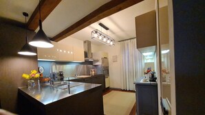A modern kitchen with a central island, pendant lighting, and a view into the dining area. - CASA "INCANTO" Charming house with breathtaking views of Lake Como. (Comun)