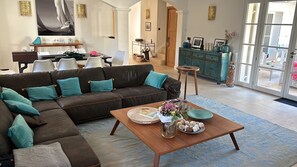 Una sala de estar con un sofá modular, una mesa de centro con objetos decorativos y vistas a un espacio exterior a través de un ventanal.