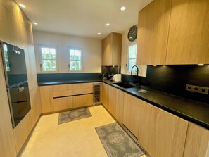Una cocina moderna con armarios de madera, encimera negra, un lavabo y un reloj en la pared.