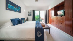 Ein Schlafzimmer mit einem großen Bett, einem Fernseher auf einer Holzkommode und einem Bild an der Wand.