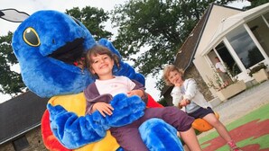 A child sitting on a large blue plush toy.