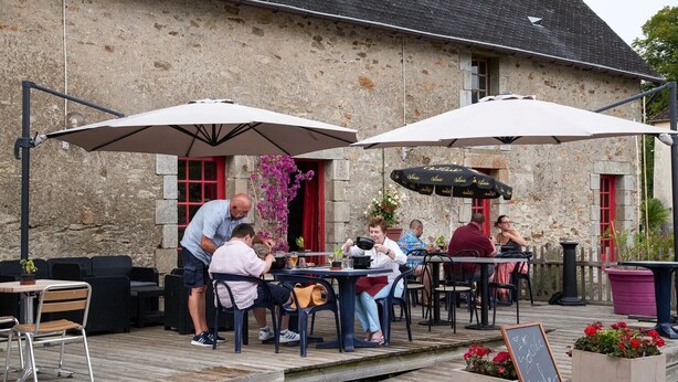 An outdoor café with stone walls, wooden deck, and outdoor seating.