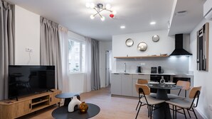 A modern living room with a TV, sofa, and dining area with chairs and a table. - Smartr Valencia Turia (Valencia)