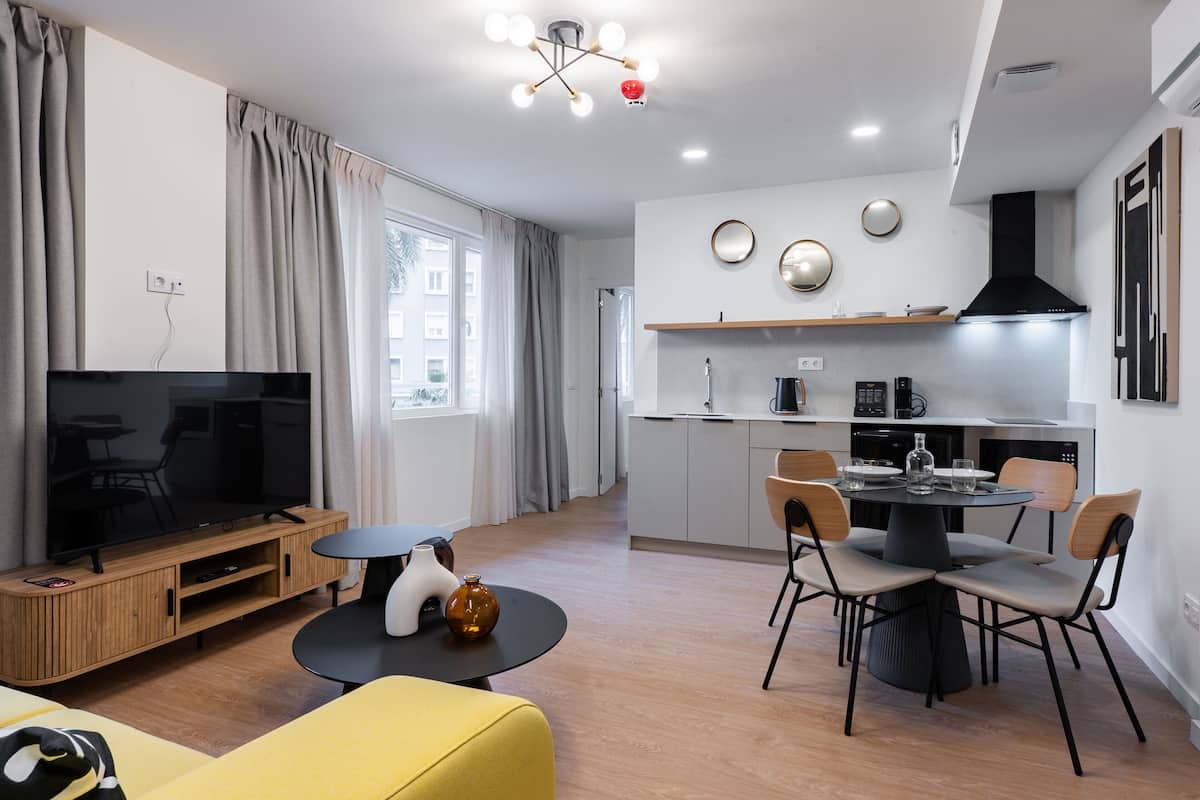 A modern living room with a TV, sofa, and dining area with chairs and a table.