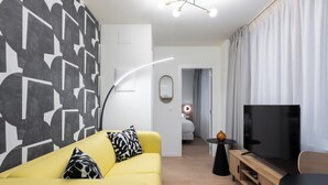 A modern living room with a yellow sofa, a flat-screen TV, and a minimalist design. - Smartr Valencia Turia (Valencia)