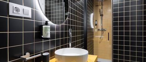A modern bathroom with a round sink, a toilet, and a shower.