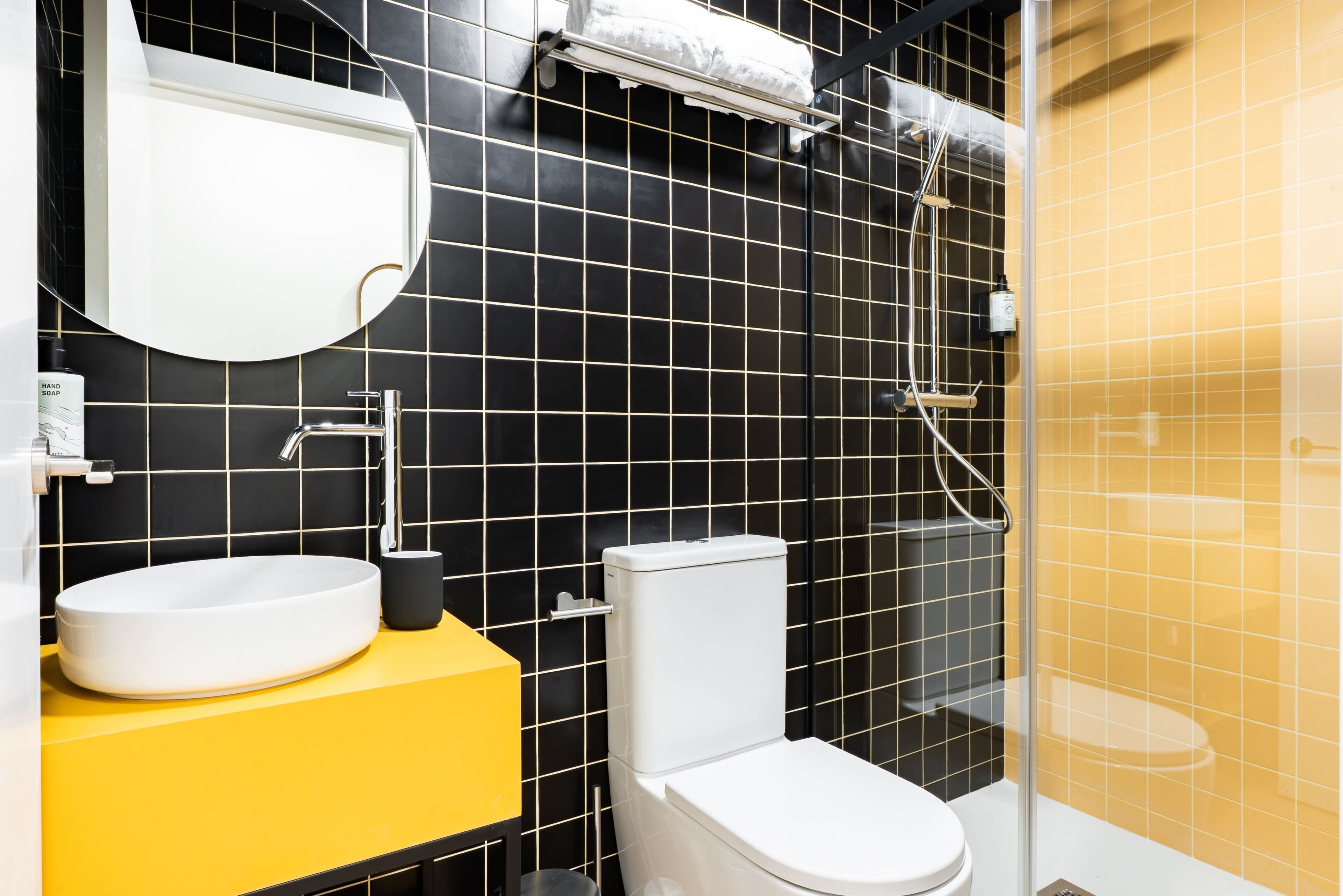 A bathroom with a white sink, a yellow countertop, a white toilet, and a glass shower enclosure.