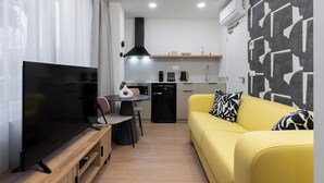 A modern living room with a flat-screen TV, a yellow sofa, and a dining area with a table and chairs. - Smartr Valencia Turia (Valencia)