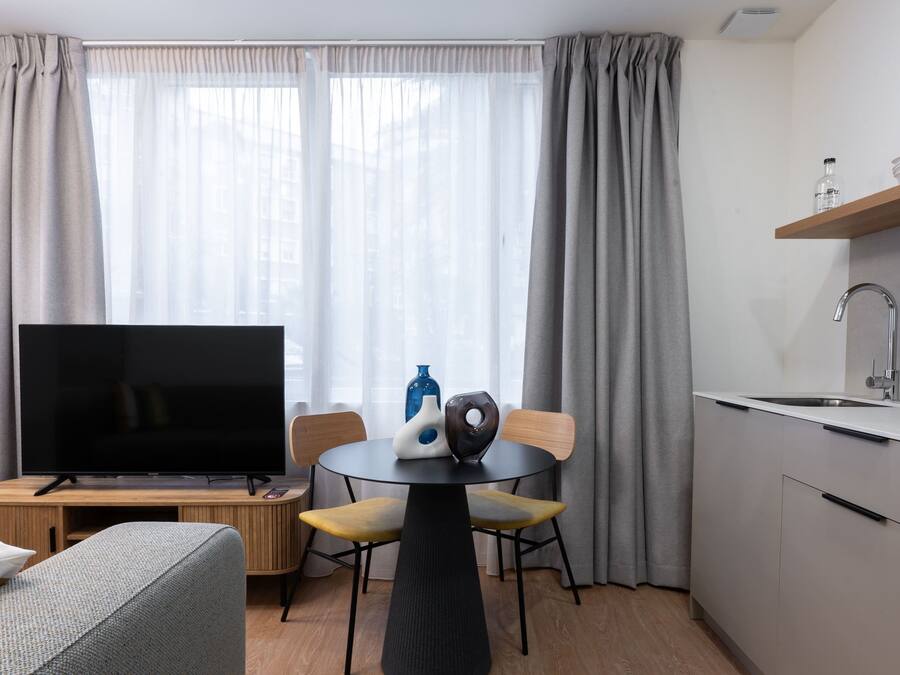 Una sala de estar moderna con una televisión de pantalla plana, una mesa de comedor redonda y un sofá.