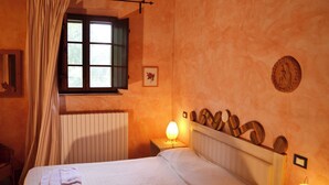 A bedroom with a bed, a window with curtains, a radiator, and a wall-mounted lamp. - Appartamento Scuderia Del Borgo (Monteleone d'Orvieto)