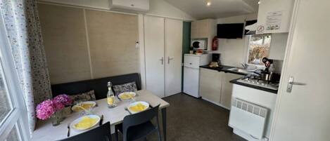 A compact kitchen with a dining area, including a table set for two, a microwave, and a small refrigerator.