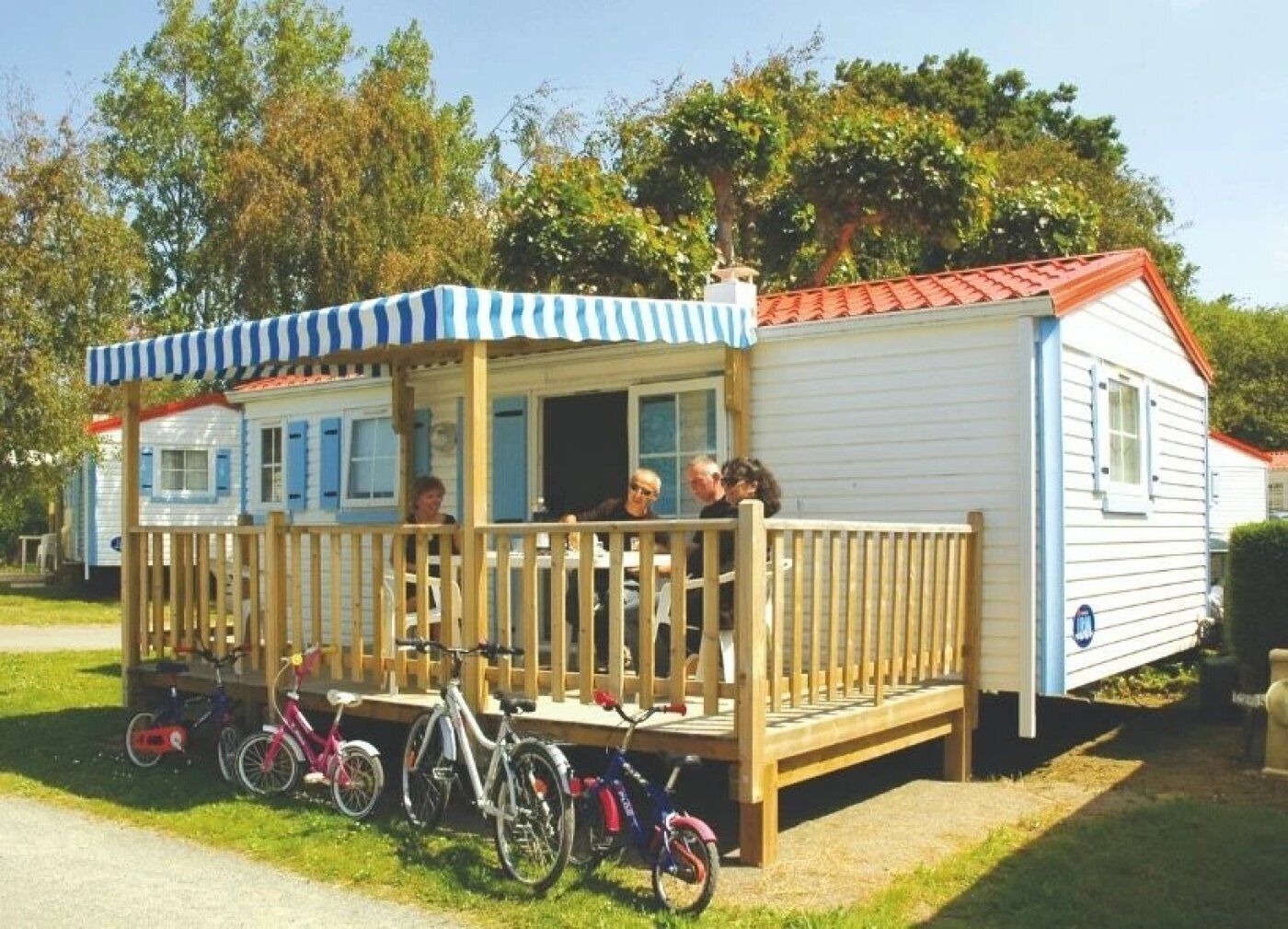 Une maison mobile dotée d’une véranda et d’un espace abrité, avec des vélos garés devant, et un ciel dégagé en arrière-plan.