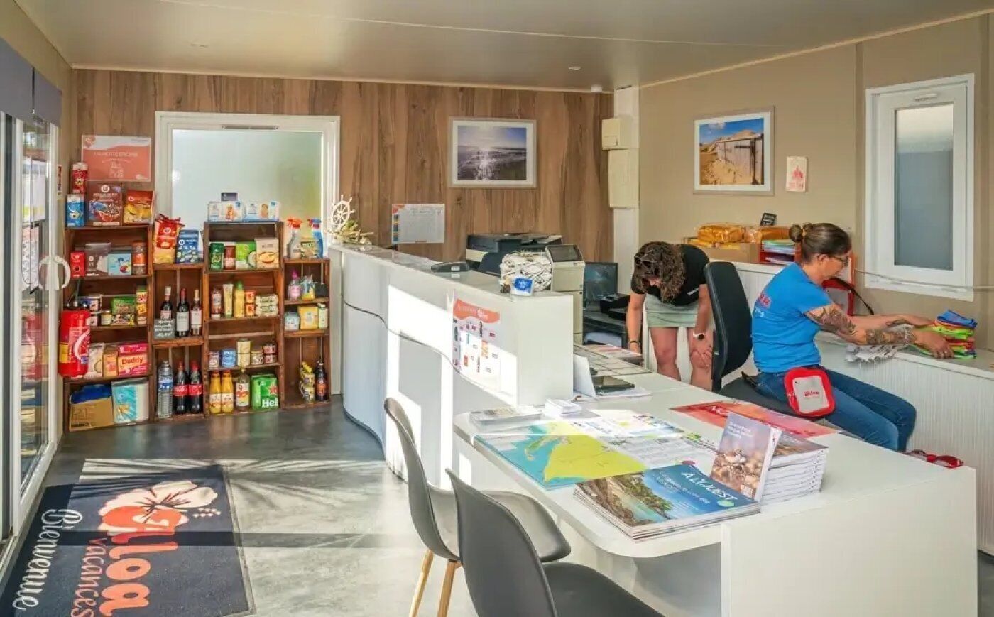 Un espace d’accueil comprenant un comptoir, un ordinateur et une étagère avec des collations et des boissons.