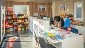 Un espace d’accueil comprenant un comptoir, un ordinateur et une étagère avec des collations et des boissons.