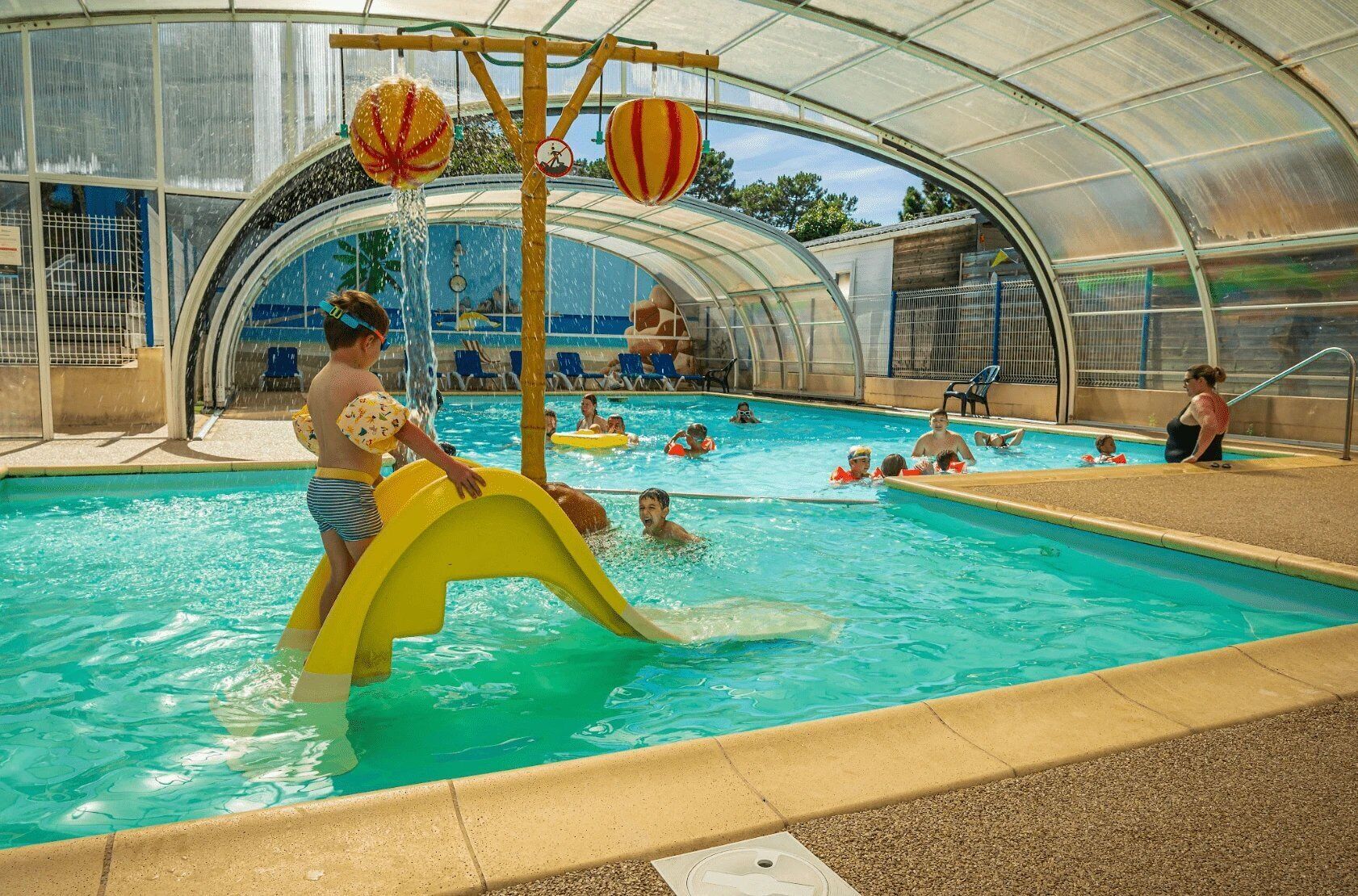 A covered swimming pool with a slide and inflatable rings.