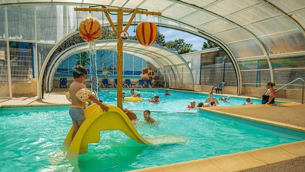 Une piscine couverte avec un toboggan et des bouées gonflables.