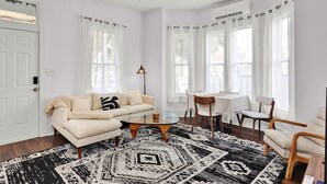 A living room with a sofa, a coffee table, and a dining table with chairs.