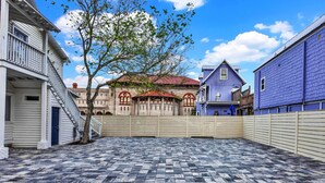 A courtyard with a tiled floor, a wooden fence, and buildings with distinct architectural styles.