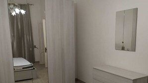 Un dormitorio con cama, armario, cómoda y espejo en la pared.