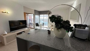 A modern kitchen with a TV, a plant, and a dining area with a view. - Flat in Roses with canal view and swimming pool AV 52 (Roses)