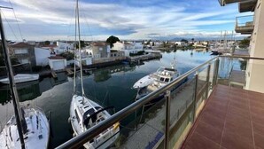 A marina with boats docked, a clear sky, and buildings in the background. - Flat in Roses with canal view and swimming pool AV 52 (Roses)