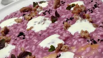 Un plato de comida de color rosa, decorado con hierbas y tostadas, sobre un plato blanco.