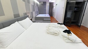 Ein Hotelzimmer mit einem großen Bett, einem begehbaren Kleiderschrank und einem Badezimmer mit einer Badewanne.