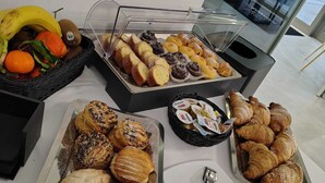 EinBuffet mit verschiedenen Backwaren, einem Obstkorb und einer Kaffeestation.