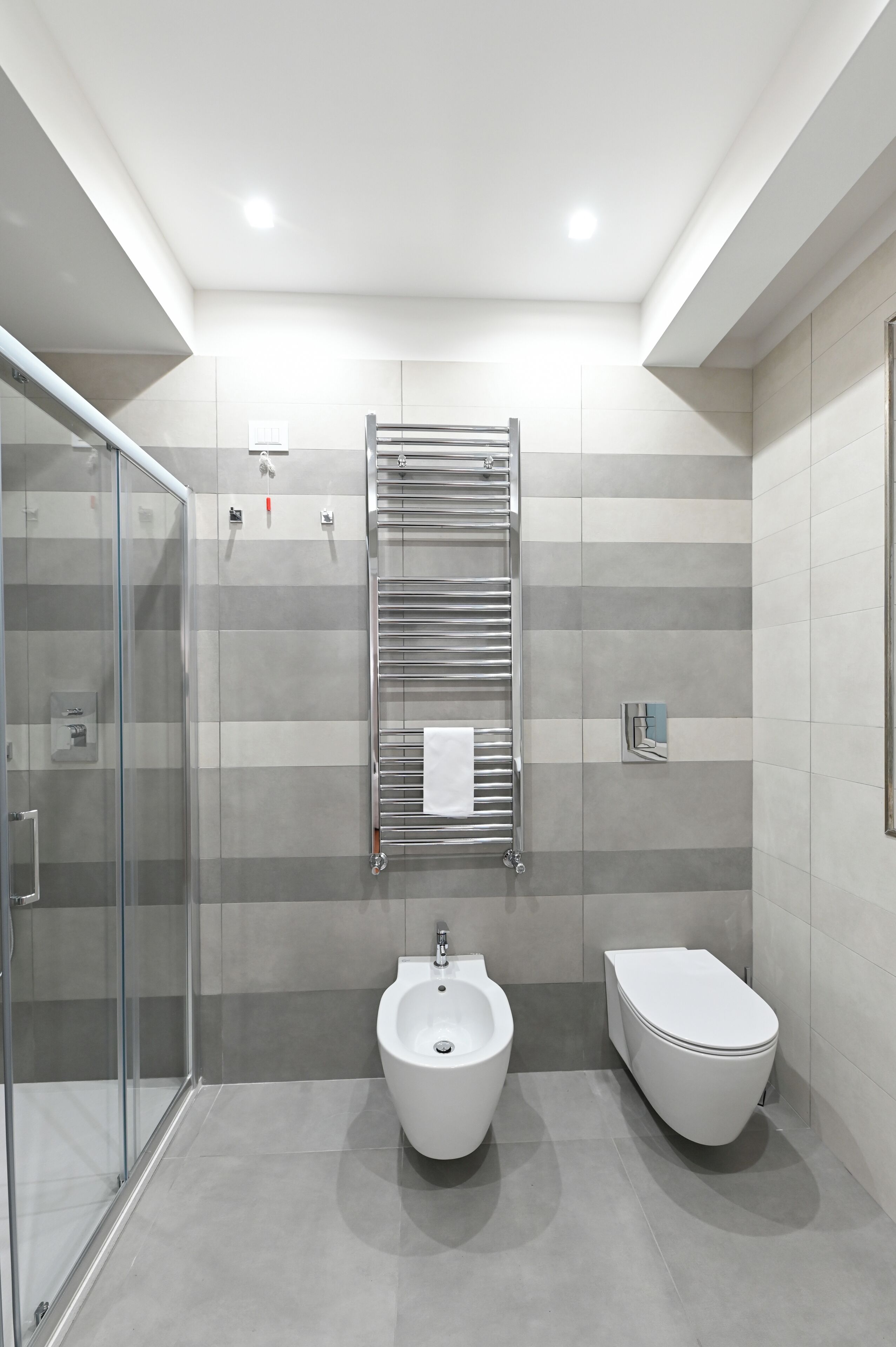A modern bathroom with a glass shower enclosure, a bidet, and a toilet.