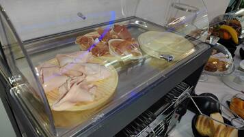 Un bufé con diversos alimentos, como embutidos, quesos y pan.