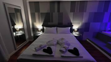A hotel room with a large bed, two bedside tables with lamps, a mirror, and a wall with a geometric pattern.