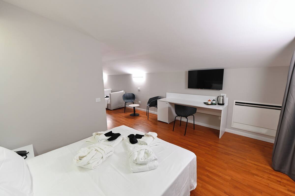 Een hotelkamer met een bed, een bureau, een stoel, een televisie en een badkamer.
