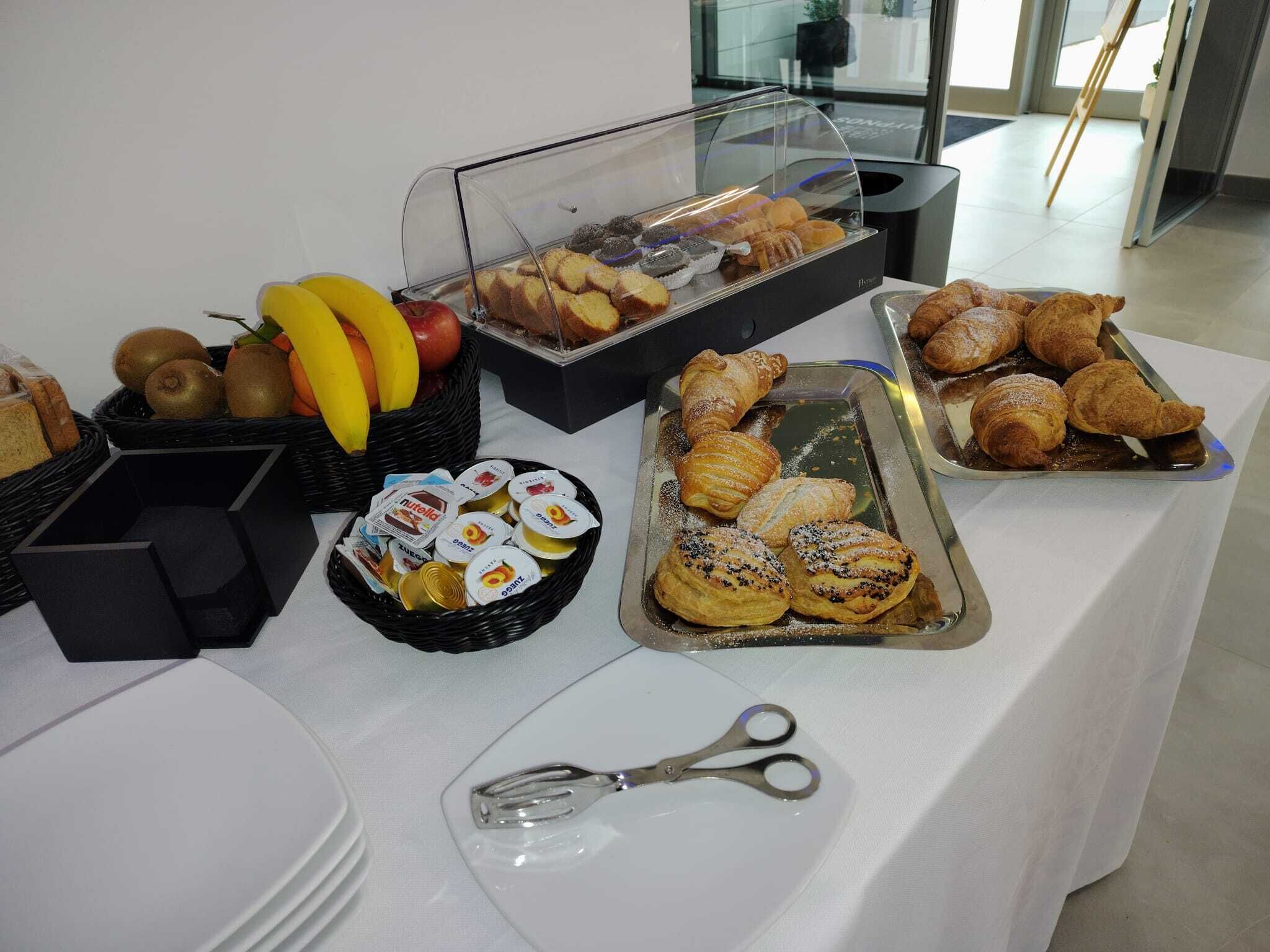 Une table de buffet proposant divers aliments, notamment des pâtisseries, des fruits et des en-cas emballés.