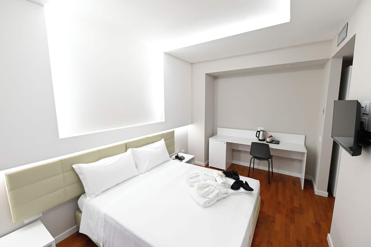Een hotelkamer met een bed, een bureau, een stoel en een televisie.