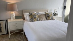 A neatly made bed with patterned pillows, a bedside lamp, and a nightstand with a framed picture.