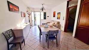 A dining area with a table and chairs, a sofa, and a kitchen counter.