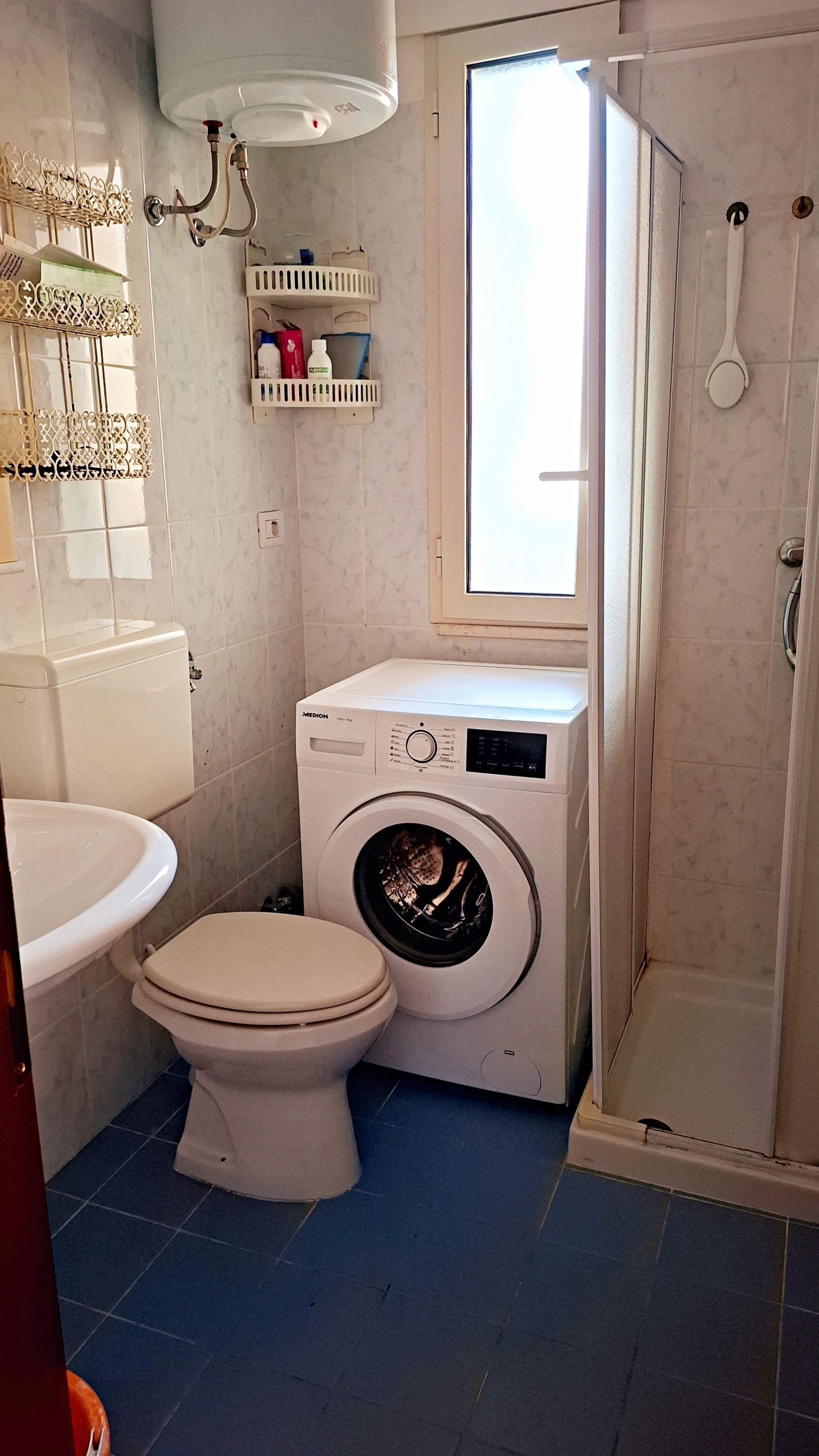 Baño pequeño con inodoro, lavadora y ducha.