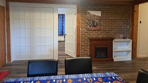 A room with a fireplace, a door, and a table with chairs. - 4-BEDROOM APARTMENT FOR ALL-INCLUSIVE WORKERS | 5 MN PONT LAVIOLETTE  (Trois-Rivières)