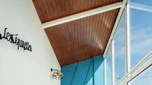 A modern room with a wooden ceiling, large windows, and a blue accent wall. - Atypical gîte Les Epinettes, 10 minutes from the beach in the Baie de Somme  (Cayeux-sur-Mer)